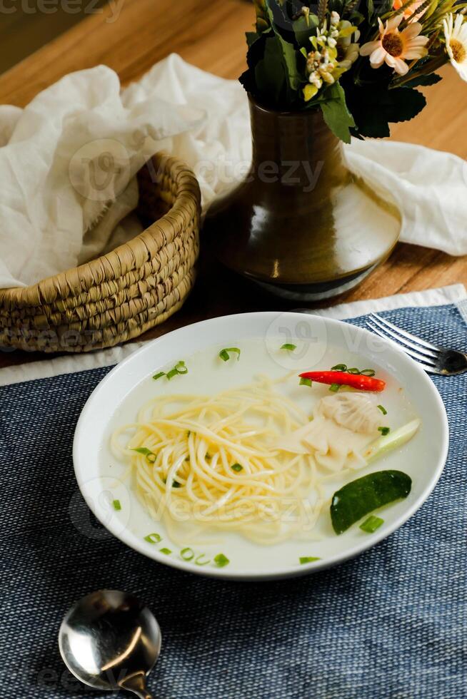 claro limón pollo Wonton incluir fideos, primavera cebolla y rojo pimienta servido en cuenco aislado en servilleta lado ver de chino sopa foto