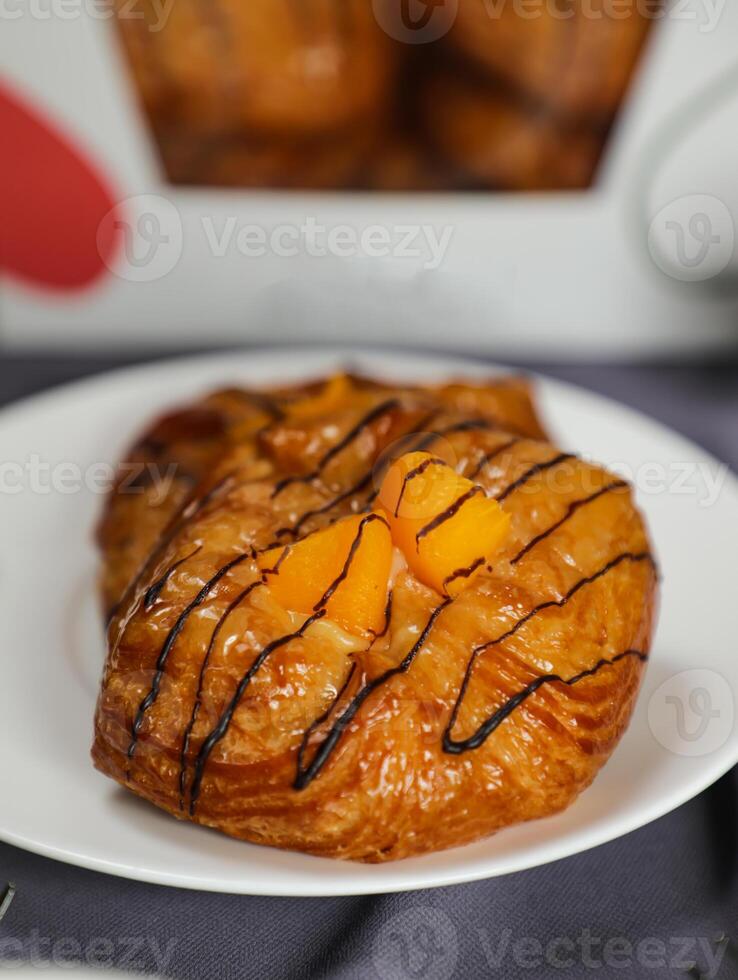 Peach Danish pastry puff served in plate isolated on napkin with side view of french breakfast baked food item on grey background photo