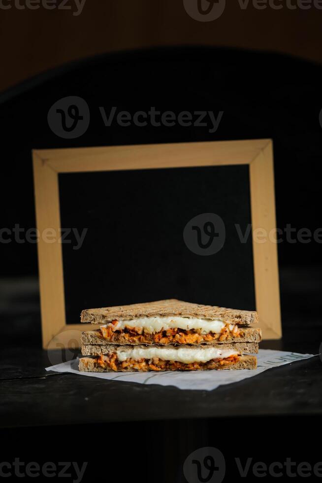 Chicken Tikka Mint Grilled Sandwich isolated on wooden board side view of fast food on dark background photo