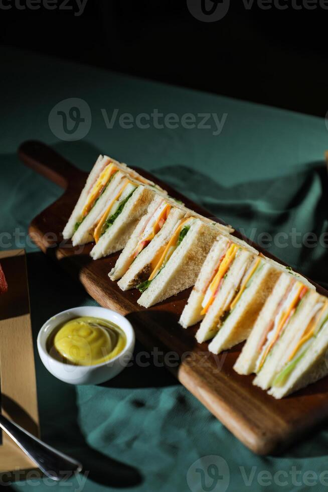 Assorted Club Sandwich isolated on wooden with mayonnaise dip and french fries bucket board side view of italian fast food on background photo