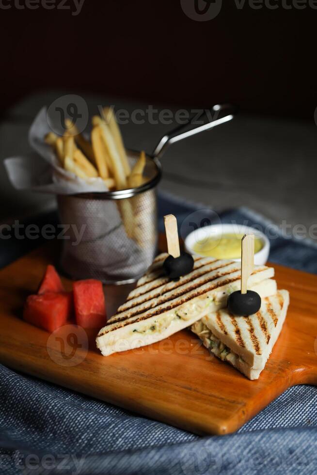 Grilled Chicken Sandwich with fries bucket served in wooden board isolated on napkin side view of breakfast food photo