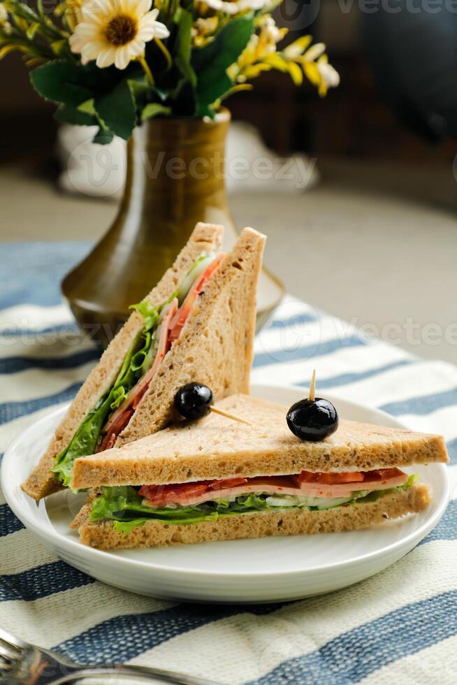 mortadela y multigrano un pan emparedado Adición con negro aceituna servido en plato aislado en servilleta lado ver de desayuno comida foto