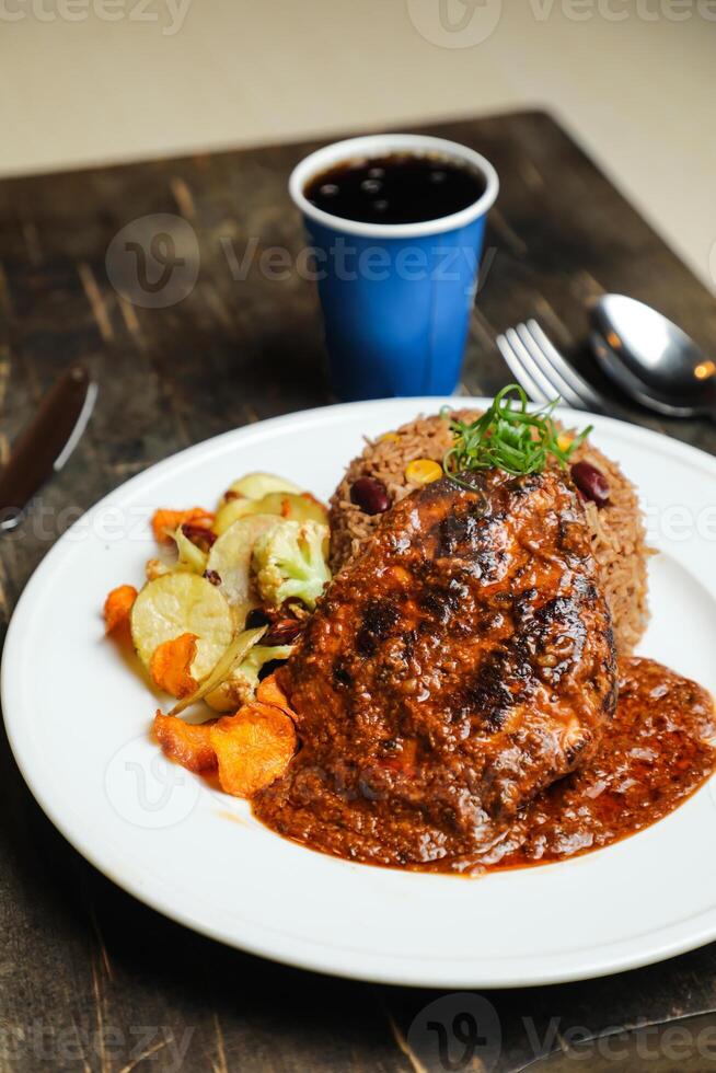 Chicken Majboos biryani rice pulao served in plate with sauce, cold drink, spoon and fork isolated on wooden board side view of arabic food photo