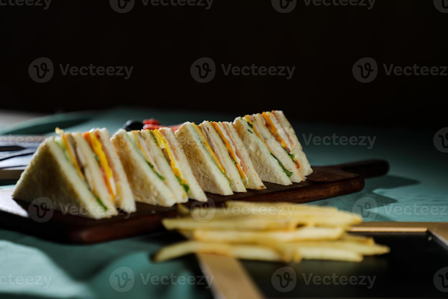 Assorted Club Sandwich isolated on wooden with mayonnaise dip and french fries bucket board side view of italian fast food on background photo