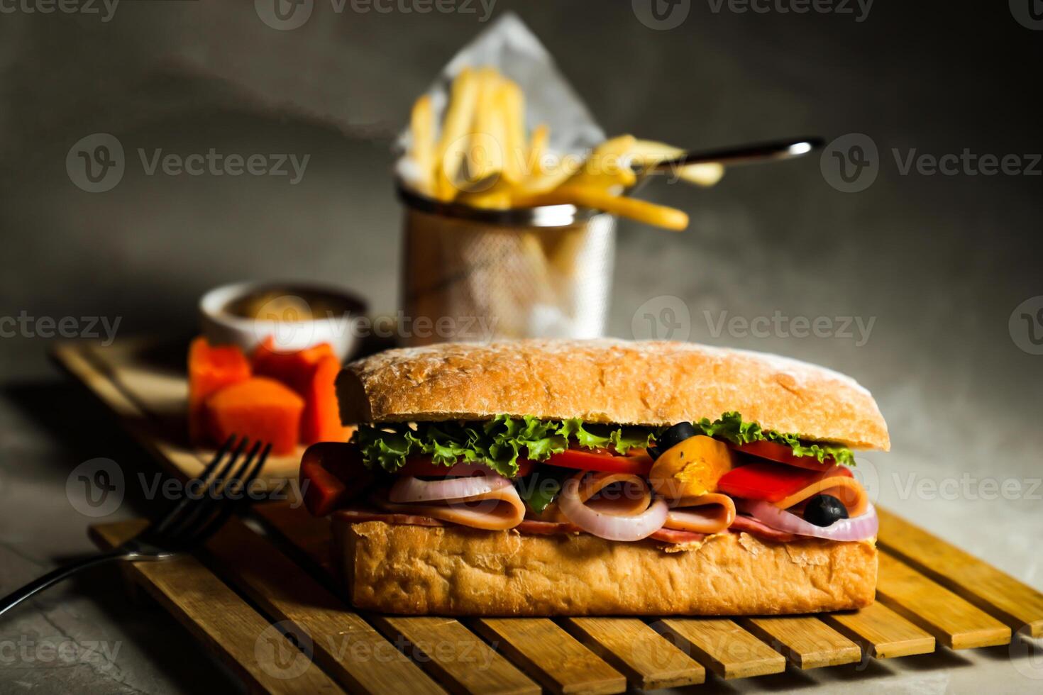 Ciabatta Smoked Ham Sandwich isolated on wooden with mayonnaise dip and french fries bucket board side view of italian fast food on grey background photo