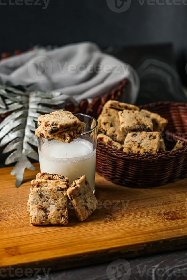 Crunchy cookies biscuits served in plate with glass of milk isolated on table side view of american cafe baked food photo