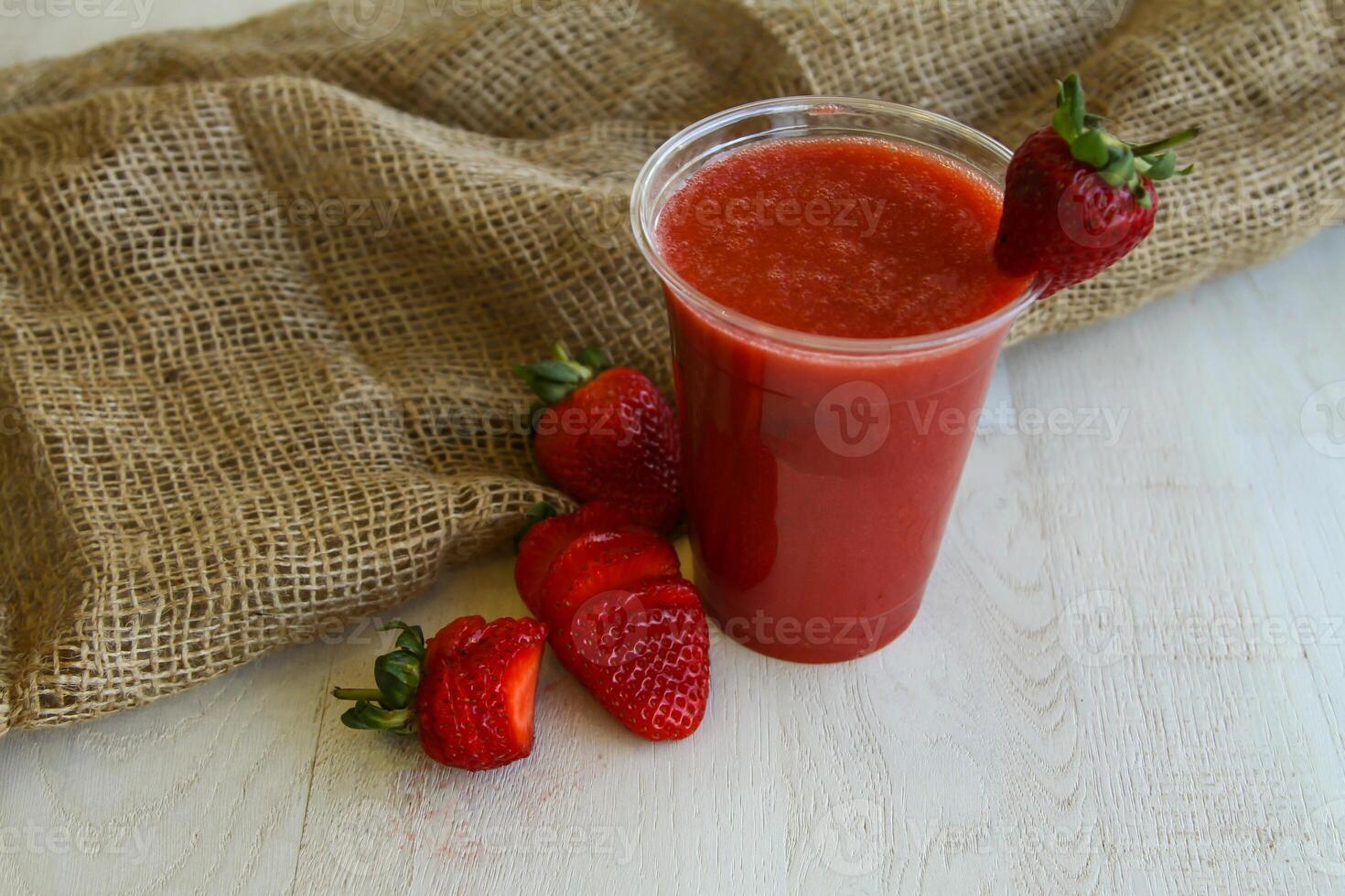 Fresco fresa jugo servido en desechable vaso aislado en mesa lado ver de sano Mañana jugo bebida foto