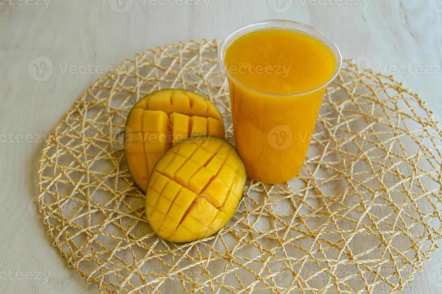 Fresh Mango Juice served in disposable glass isolated on table side view of healthy morning juice drink photo