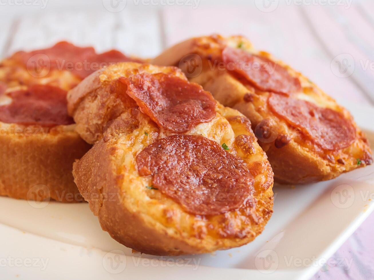 GARLIC BREAD TOPPED WITH CHEESE AND PEPPERONI served in dish isolated wooden table top view arabic food appetizer photo