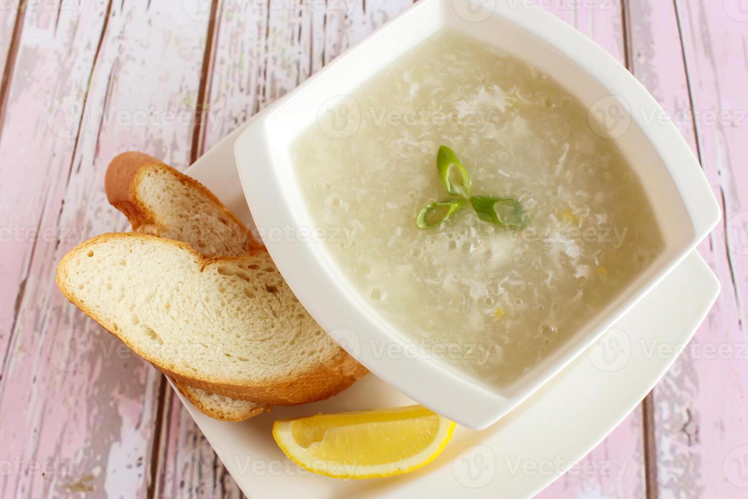 CHICKEN CORN SOUP with bread and lemon slice served in bowl isolated on table closeup top view of hot soup photo