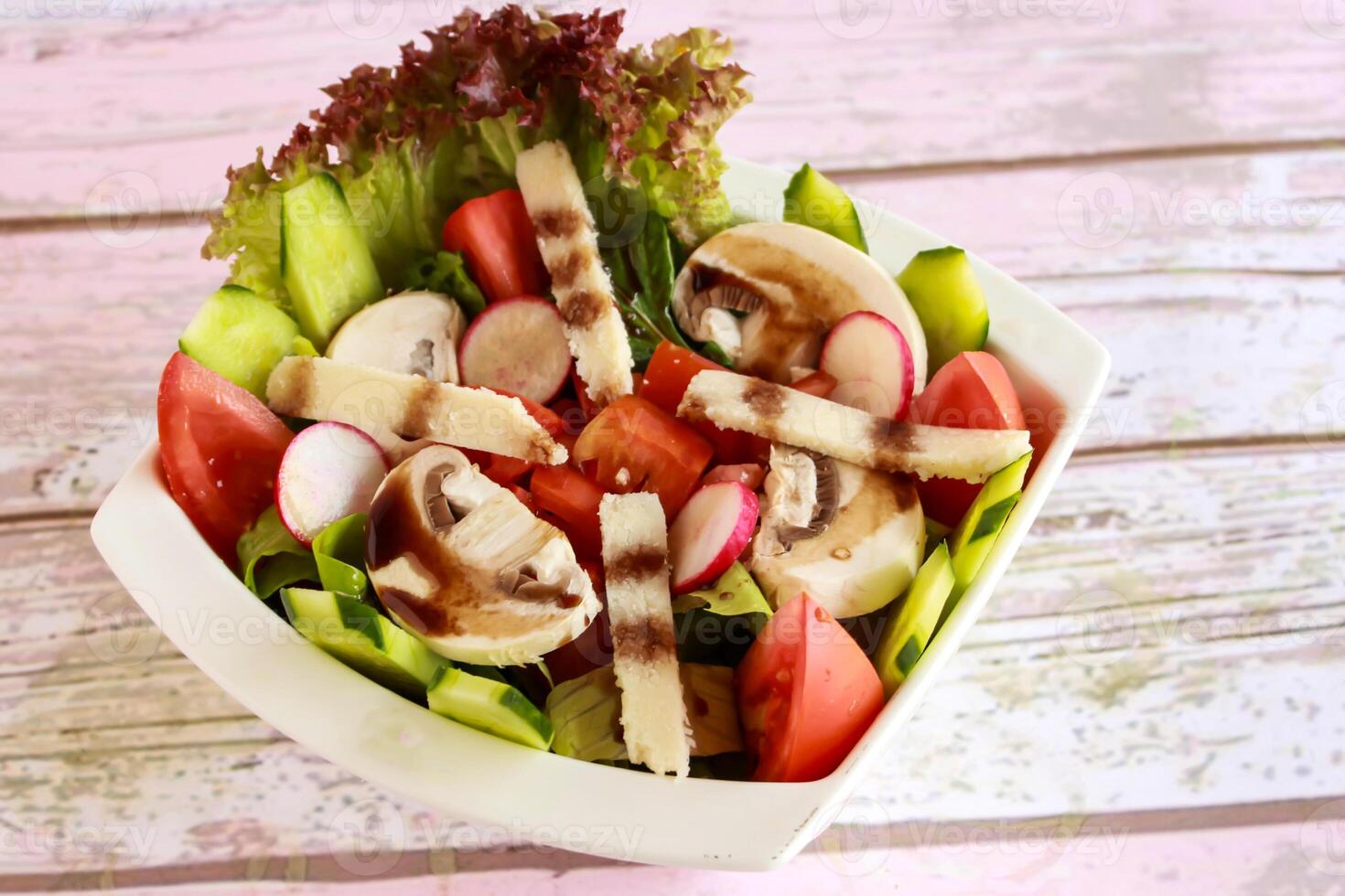 Mixed Salad with tomato, cucumber, mushroom, lettuce leave and cheese served in dish isolated on table closeup top view of healthy organic food photo