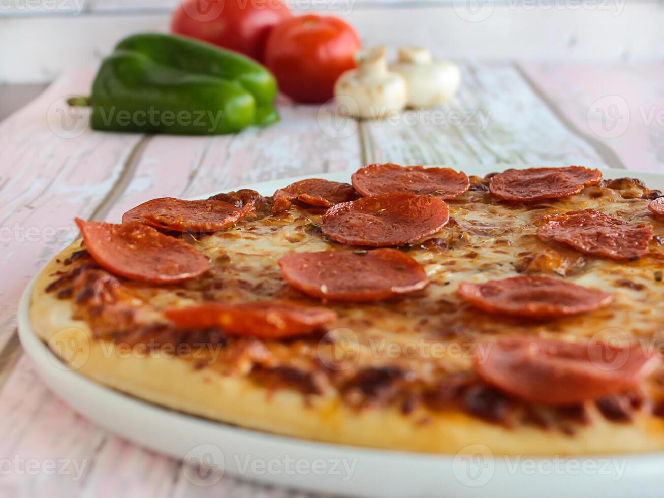 pepperoni Pizza de cerca Adición con Pimiento, champiñón, tomate y aceitunas servido en plato aislado en mesa lado ver de Arábica comida rápida foto