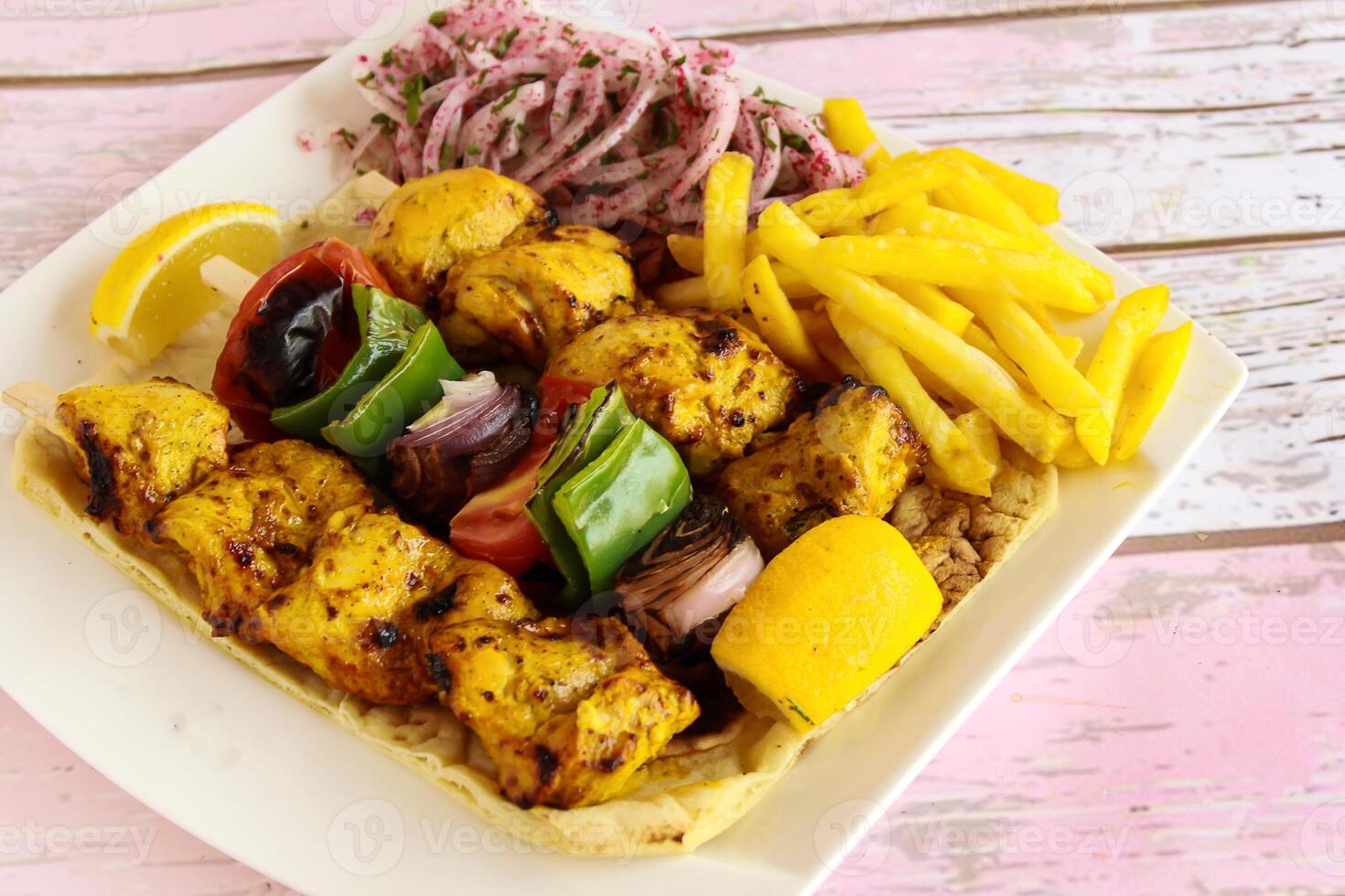 Joojeh Kabab with Skewer and shahlik with lemon, onion and french fries served in dish isolated wooden table top view of tandoori grill bbq food photo