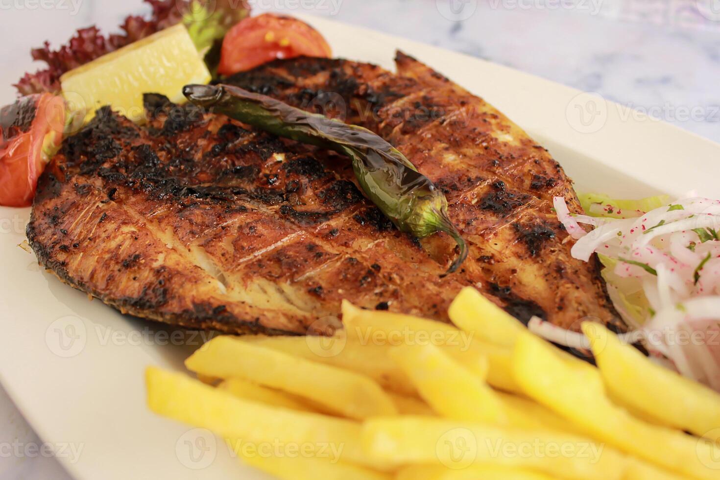 Grill Supreme Fish with french fries served in dish isolated on table closeup top view of grilled seafood photo