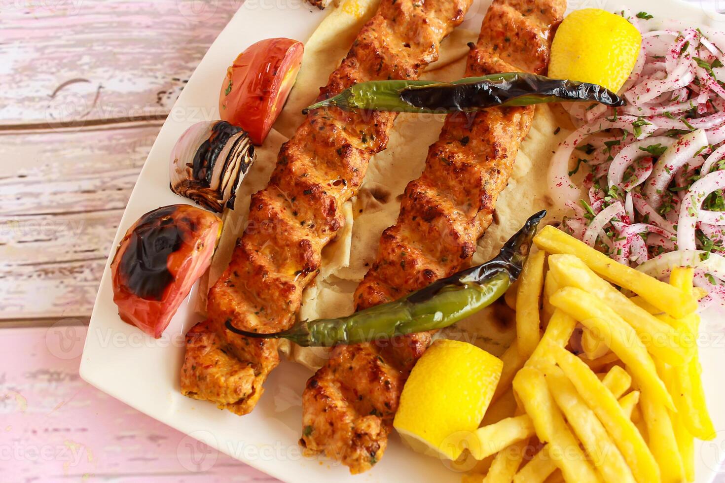 pollo seekh kabab con picado carne, limón, cebolla y francés papas fritas servido en plato aislado de madera mesa parte superior ver de tandoori parrilla barbacoa comida foto