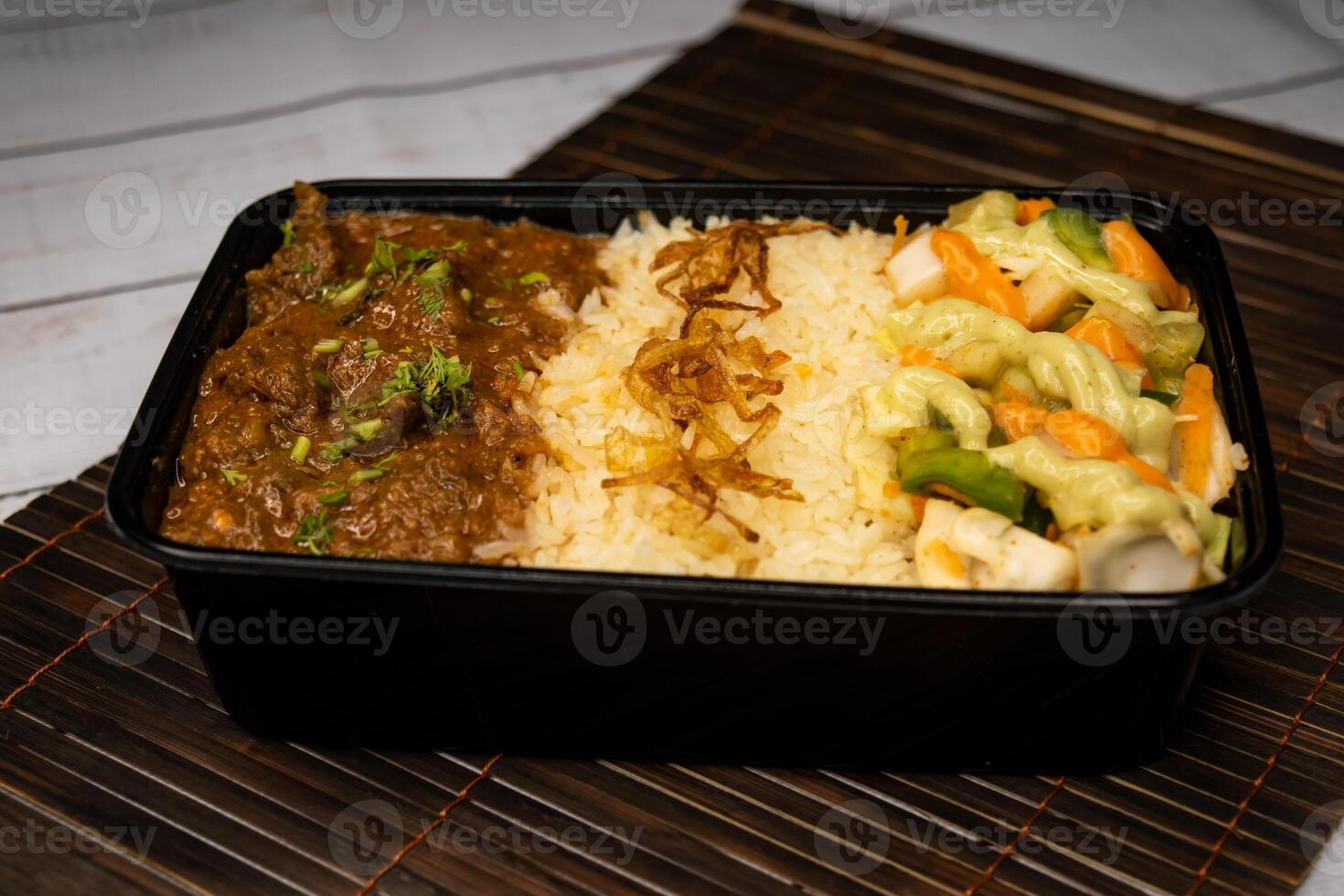 Beef Bhuna with pulao biryani rice with cucumber, dip sauce and lemon slice served in dish isolated on wooden table side view of bangladeshi and indian spicy food photo