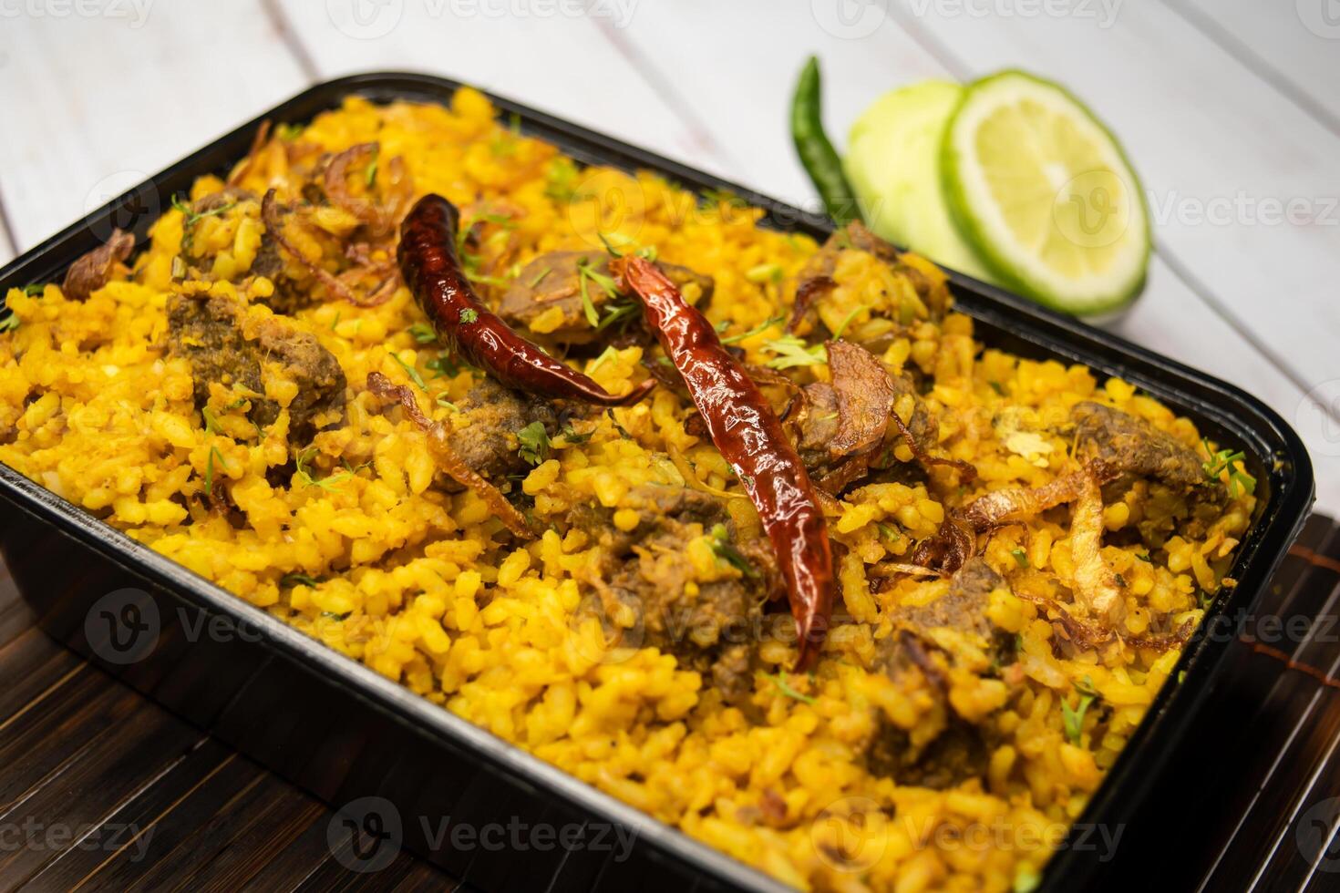 Achari beef khichuri biryani rice pulao with cucumber and lemon slice served in dish isolated on wooden table side view of bangladeshi and indian spices lunch food photo