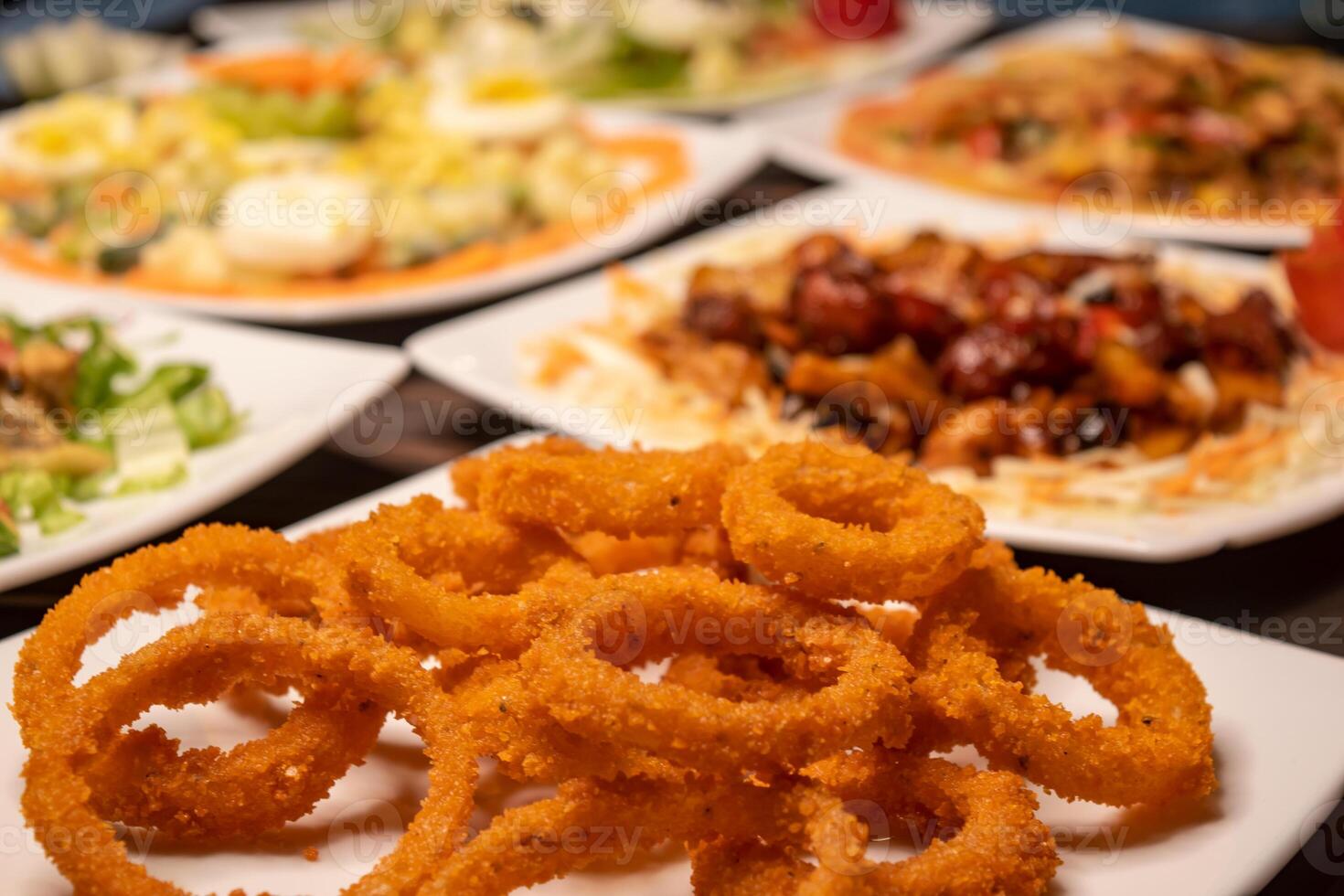 Assorted salads variety with chicken vegetable cashew nut salad, classic Greece salad, russian salad, grilled chicken, munchies, fried onion rings served isolated closeup side view of healthy food photo