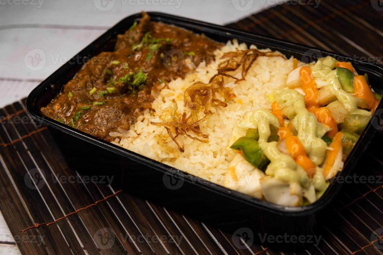 Beef Bhuna with pulao biryani rice with cucumber, dip sauce and lemon slice served in dish isolated on wooden table side view closeup of bangladeshi and indian spicy lunch food photo