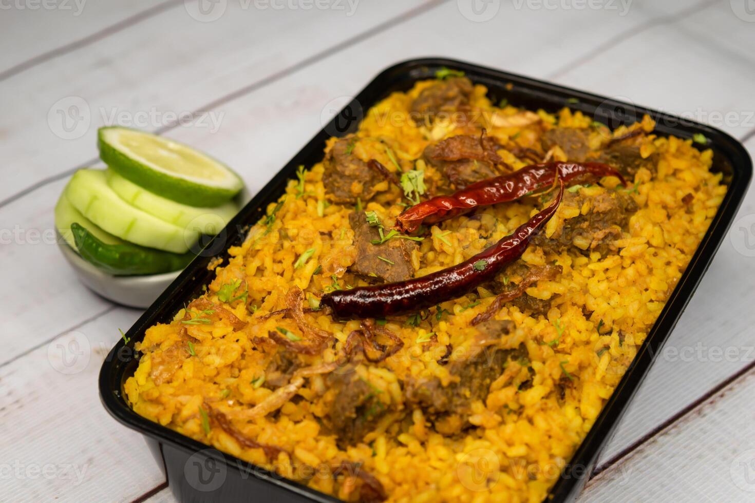 Achari beef khichuri biryani rice pulao with cucumber and lemon slice served in dish isolated on wooden table side view of bangladeshi and indian spicy lunch food photo