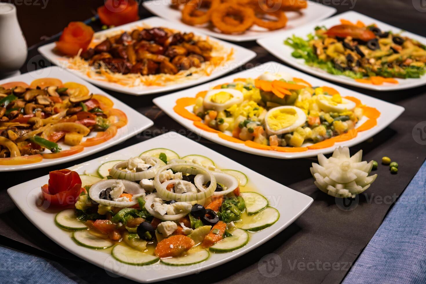 Assorted salads variety with chicken vegetable cashew nut salad, classic Greece salad, russian salad, grilled chicken salad, munchies and fried onion rings served isolated side view of healthy food photo
