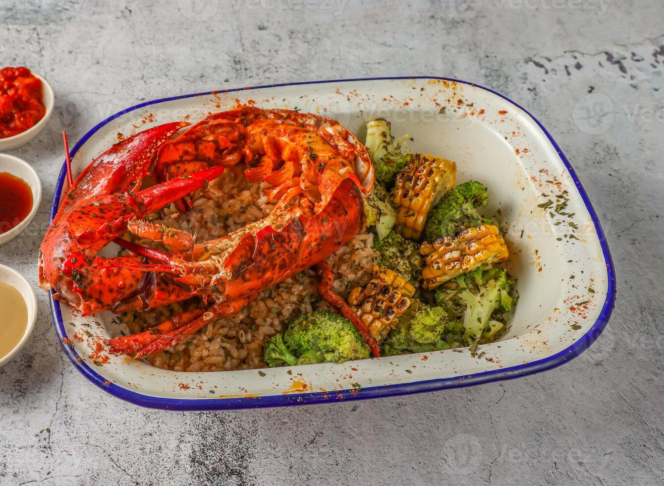 half boston lobster with fried rice, grilled corn and broccoli served in isolated on grey background top view of singaporean food photo