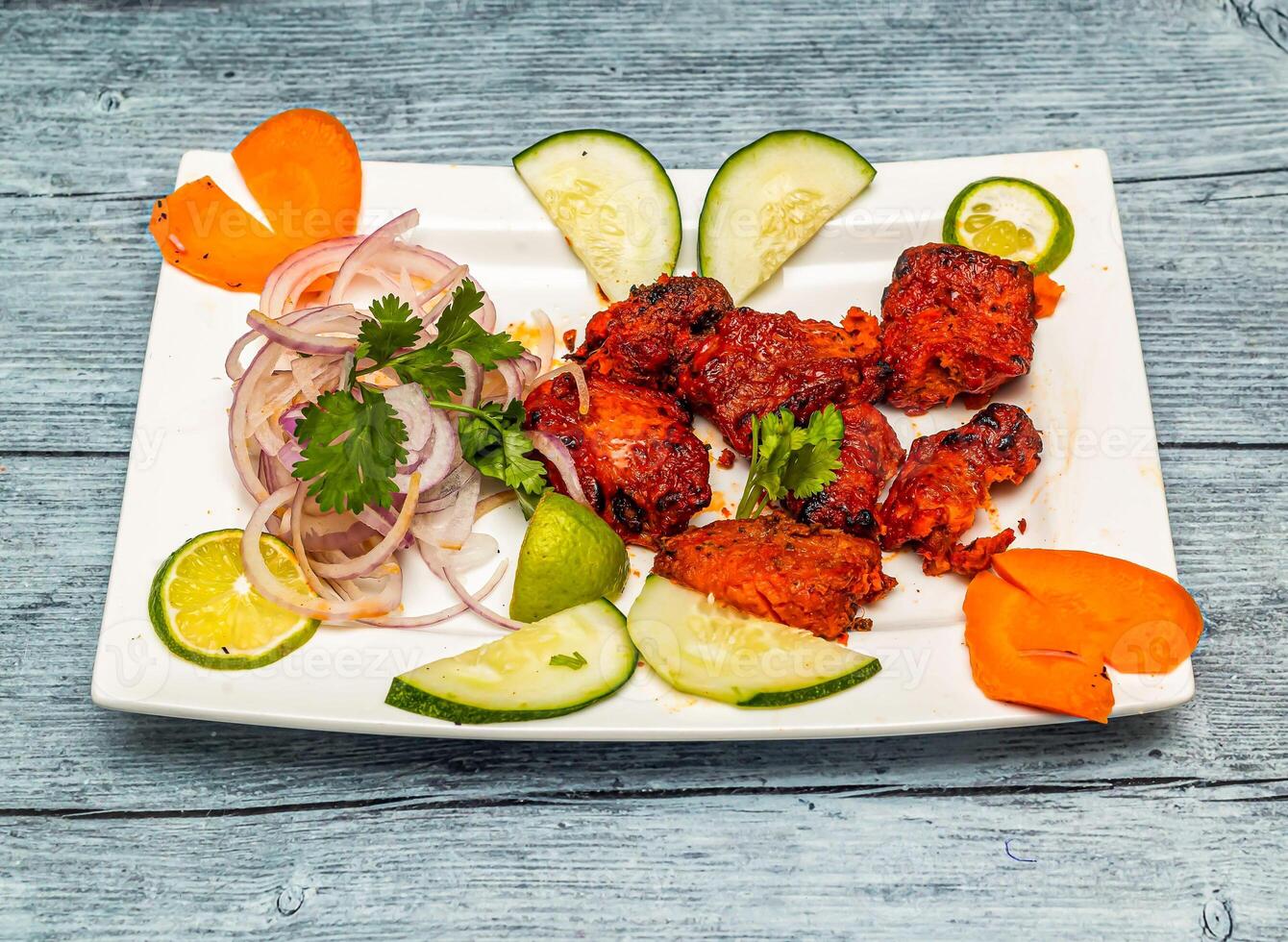 saffron fish tikka with lemon and onion served in dish isolated on wooden table top view of indian spicy food photo