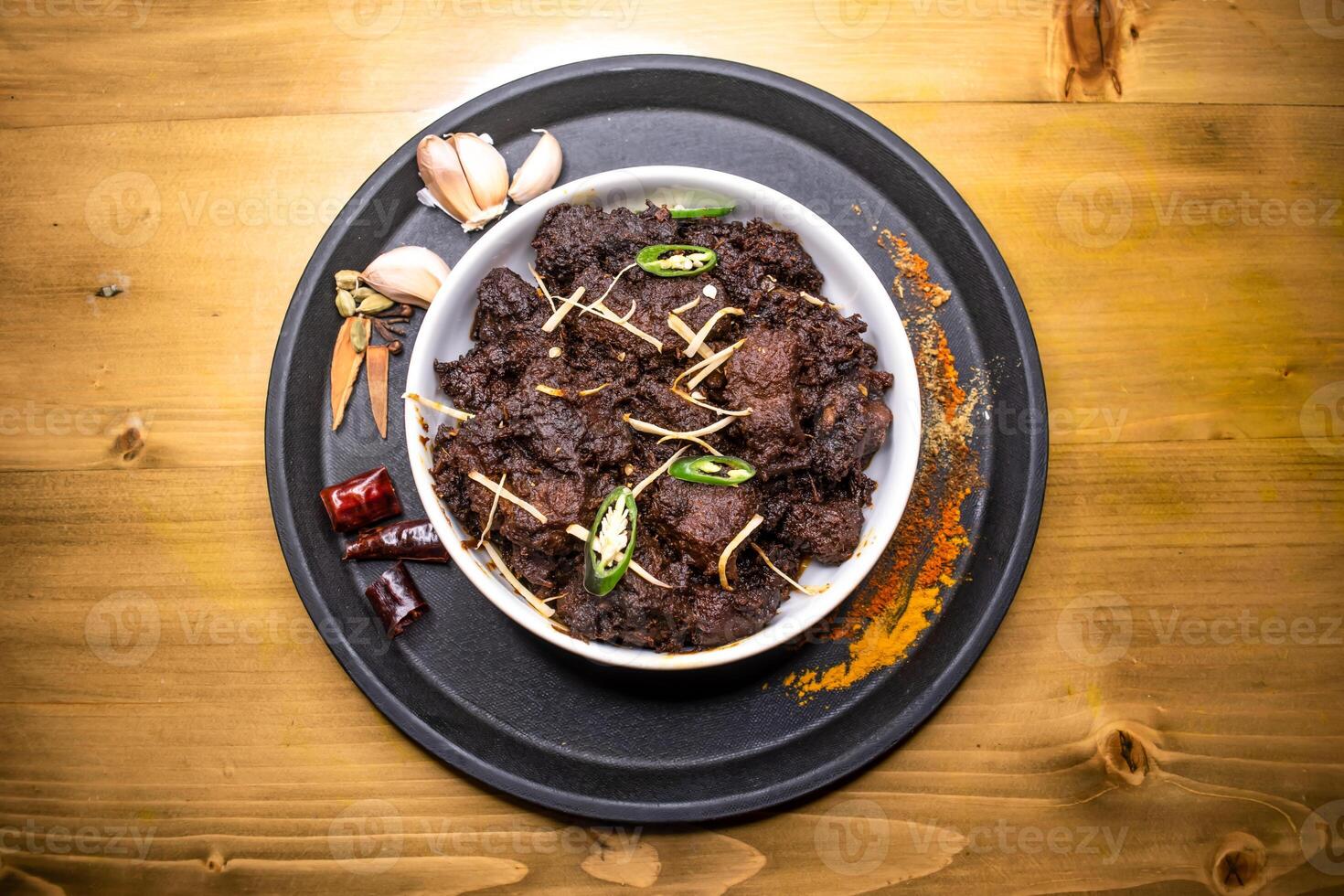 Kala Bhuna Gosht karahi served in dish isolated on wooden background top view indian spices, bangladeshi and pakistani food photo