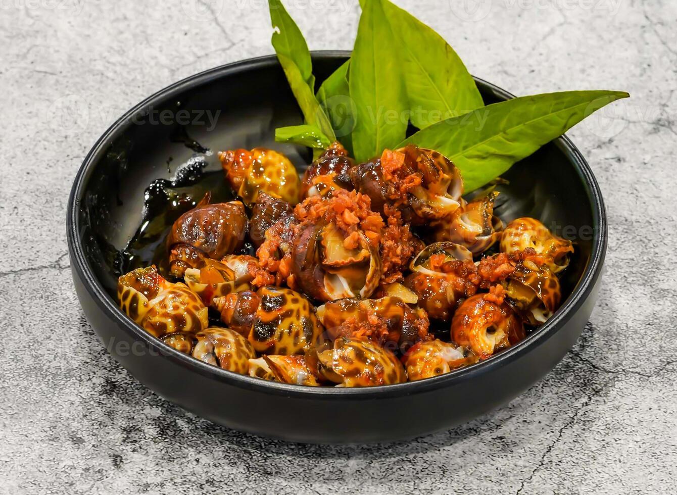 salted snails or oc huong muoi tac, botoi served in dish isolated on grey background top view of singapore seafood photo