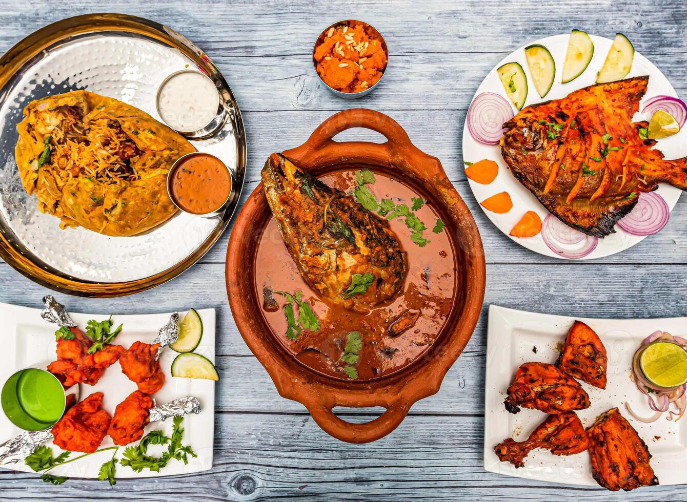fish head curry, darbar royal potlam biryani rice, tandoori chicken, grill pomfret fish, Rava kesari halwa sweet, chicken lollipop, served in dish isolated wooden table top view of indian spicy food photo