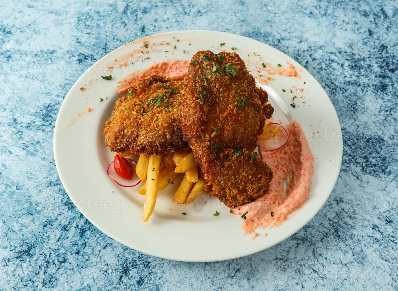 crumbed chicken with french fries served in plate isolated on background top view of italian food photo