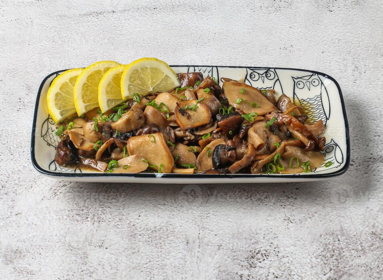 sauteed wild mushroom with lemon slice served in dish isolated on grey background top view of singapore food photo