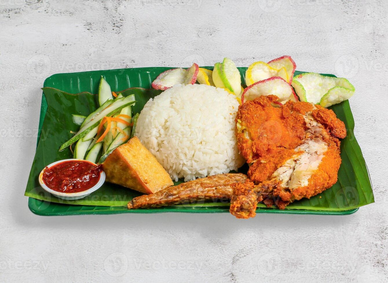 ayam penyet with rice, salad and chilli sauce served in dish isolated on banana leaf top view of singapore food photo