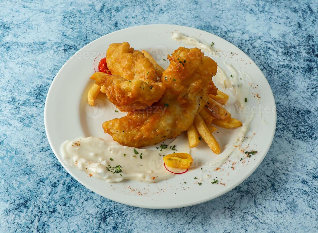 Battered Fish with french fries, lemon and dip served in plate isolated on background top view of italian food photo