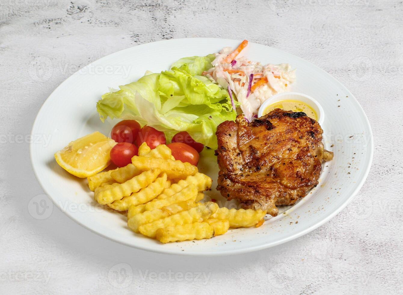 grilled chicken chop with lemon, salad, tomato and dip served in dish isolated on banana leaf top view of singapore food photo