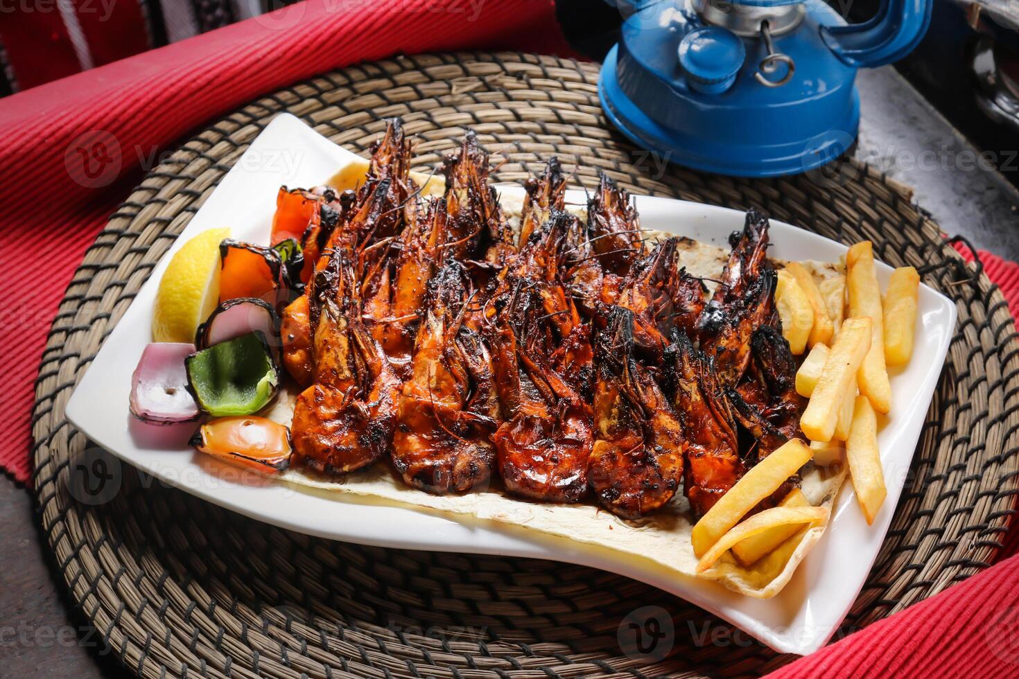 Grilled Shrimp with fries and salad served in dish isolated on red mat top view on table arabic food photo