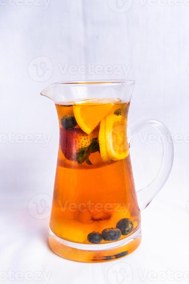 Fruit black tea include lemon slice, strawberry and blueberry served in jar isolated on background side view of iced drink photo