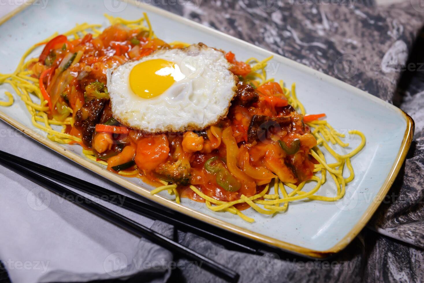 American Chopsuey with sunny side up egg, noodles, vegetables and chicken served in dish isolated on food table top view of middle east spices photo