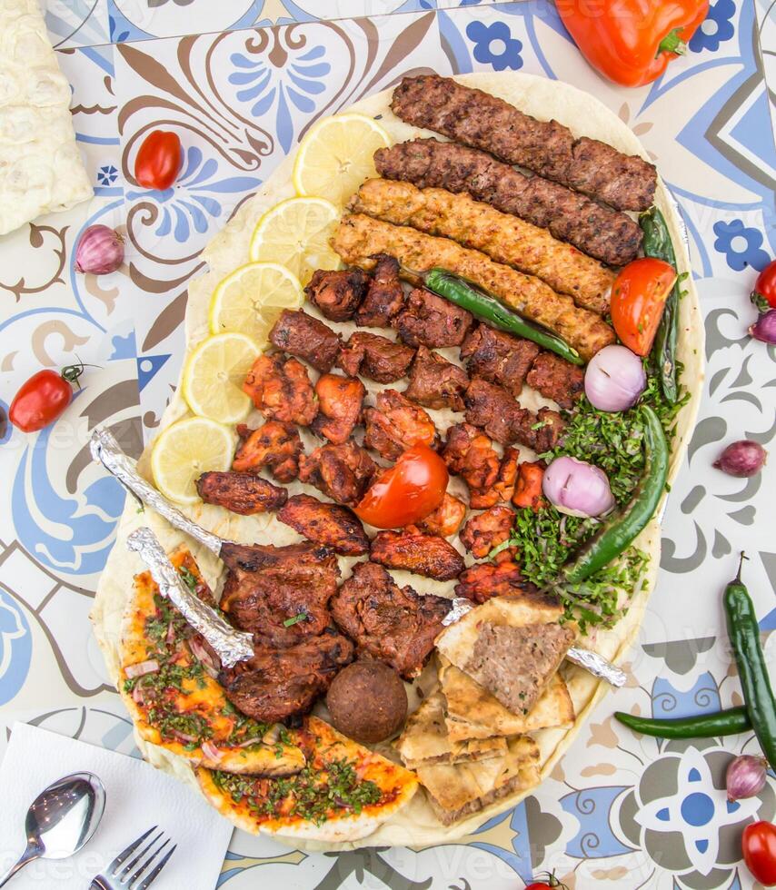 Assorted mix grills with tikka boti seekh kabab of lamb chops, pita bread, flafel, chicken, beef, lamb, mutton bbq platter served in dish isolated on table top view of arabic food photo