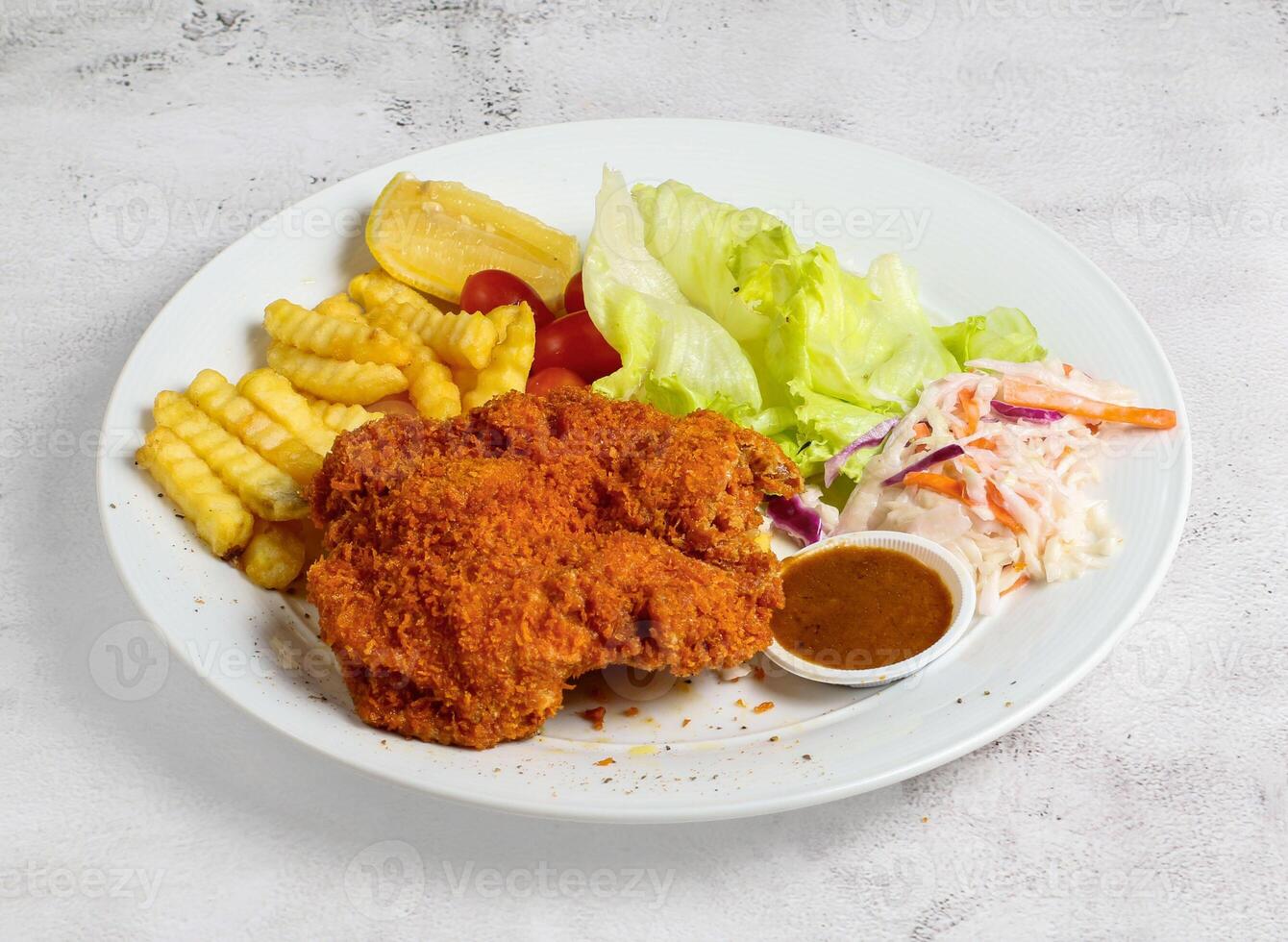 Chicken cutlet or chop with salad, lime and french fries served in dish isolated top view of singapore food photo