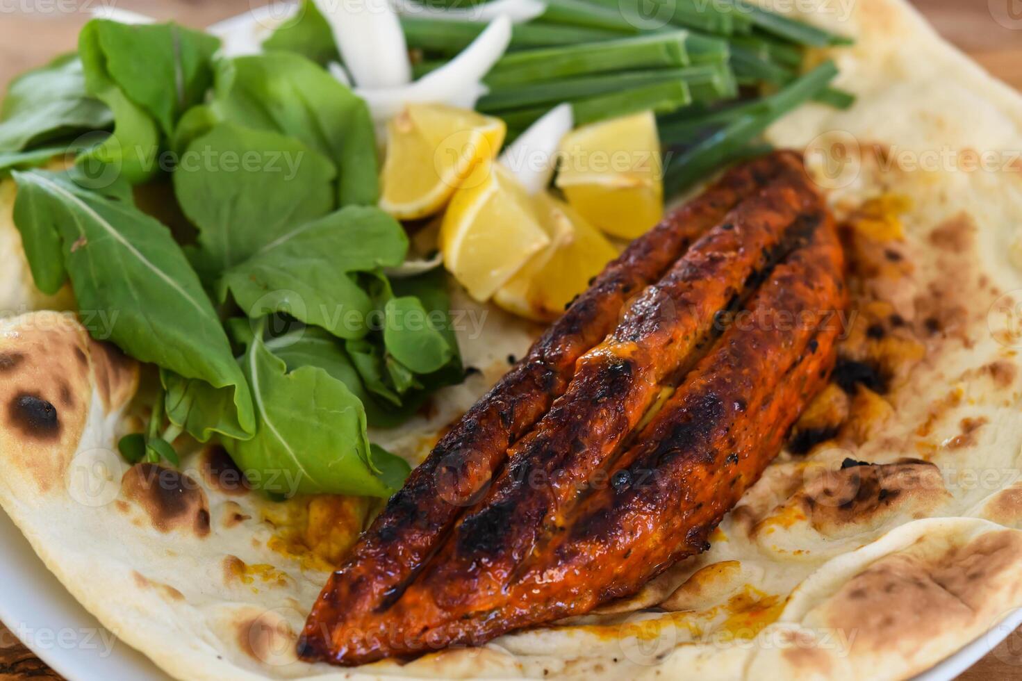 Chicken Stuffed With Cheese meat seekh kebab with bahraini bread tandoori nan, lime and salad served in dish isolated on wooden table top view middle eastern grills food photo