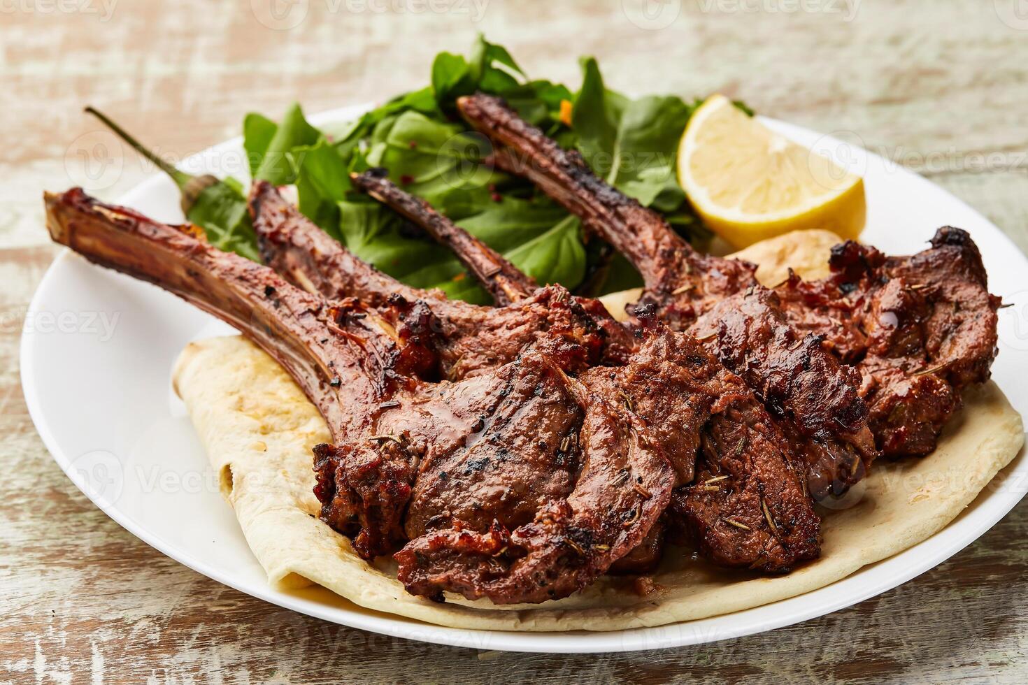 Grilled Lamb Chops with lemon slice ad salad served in dish isolated on table top view of arabic food photo