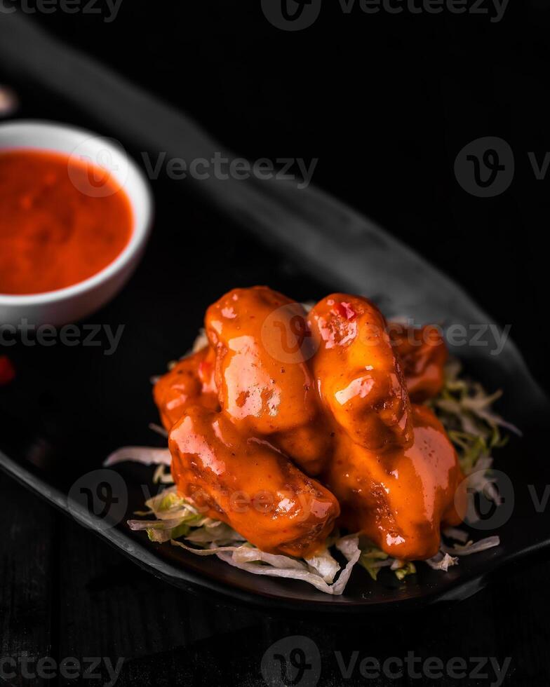 Dynamite Chicken with chili sauce served in dish isolated on wooden table side view of arabic foods photo