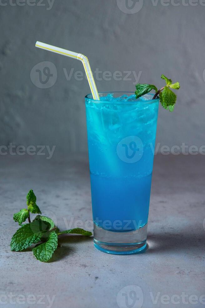 Healthy Blue Lagoon Mojito soda served in glass with straw side view on grey background photo