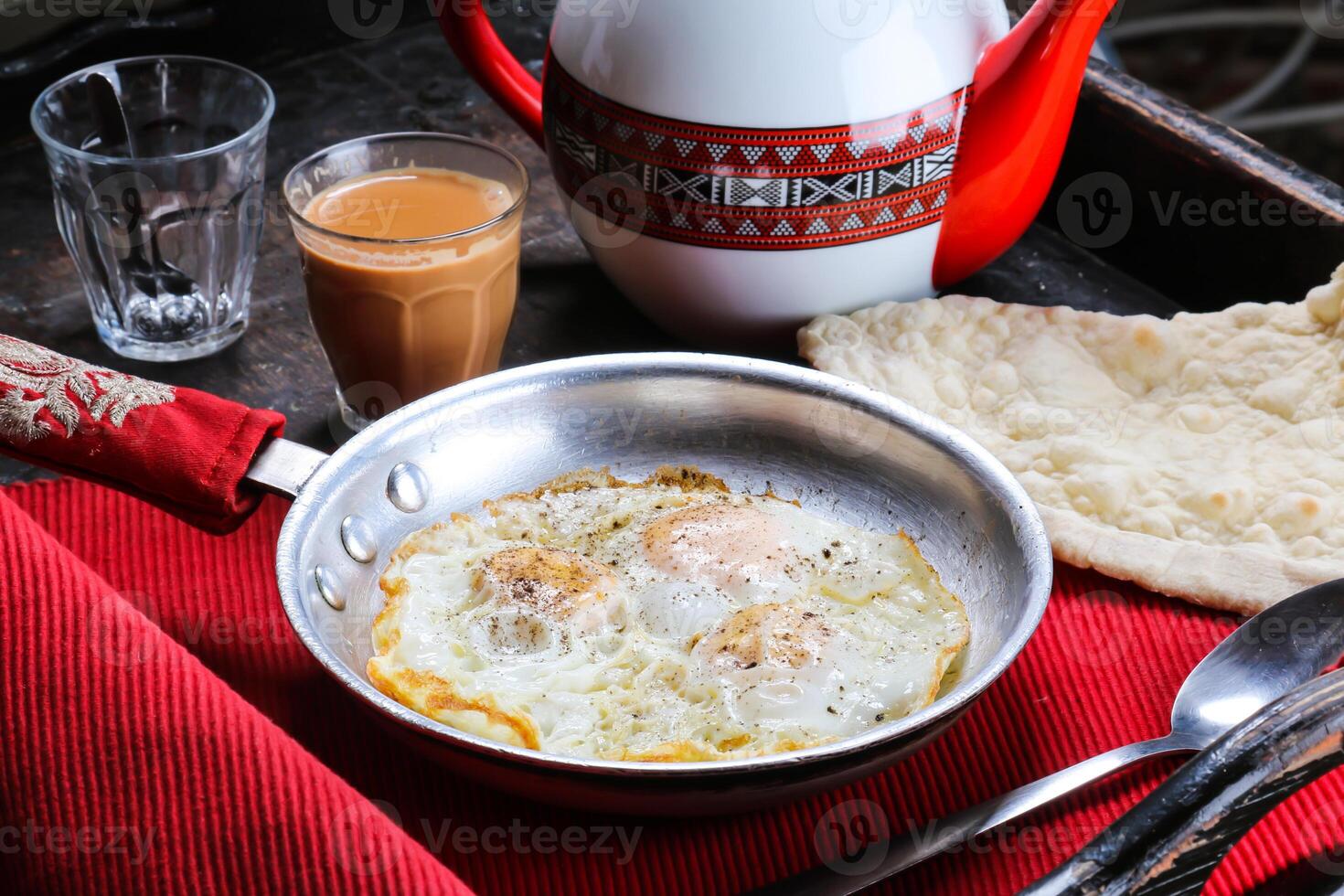 Fried Egg with bread, coffee and teapot served in dish isolated on red mat top view on table arabic food photo