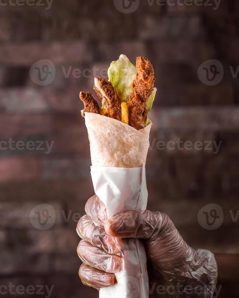 Chicken Wrap in hand isolated side view of arabic food photo