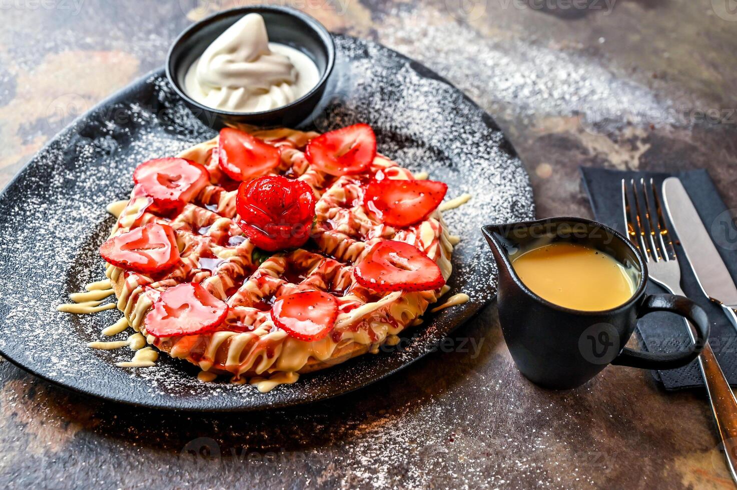 Crusted Strawberry waffle with white chocolate, whipped cream, pistachio, knife and fork served in dish isolated on dark background top view cafe dessert food photo