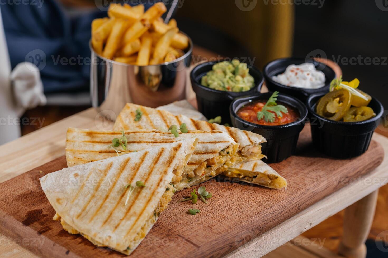 Chicken Quesadillas taco wrap slice with chili sauce and french fries bucket served on wooden board isolated on table top view of arabic fastfood photo