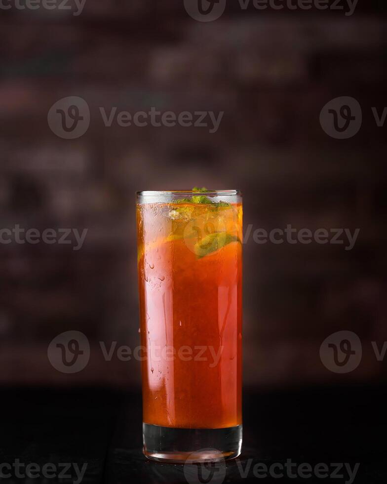 Peach ice tea with lemon and mint served in glass isolated on wooden table side view of arabic drink photo