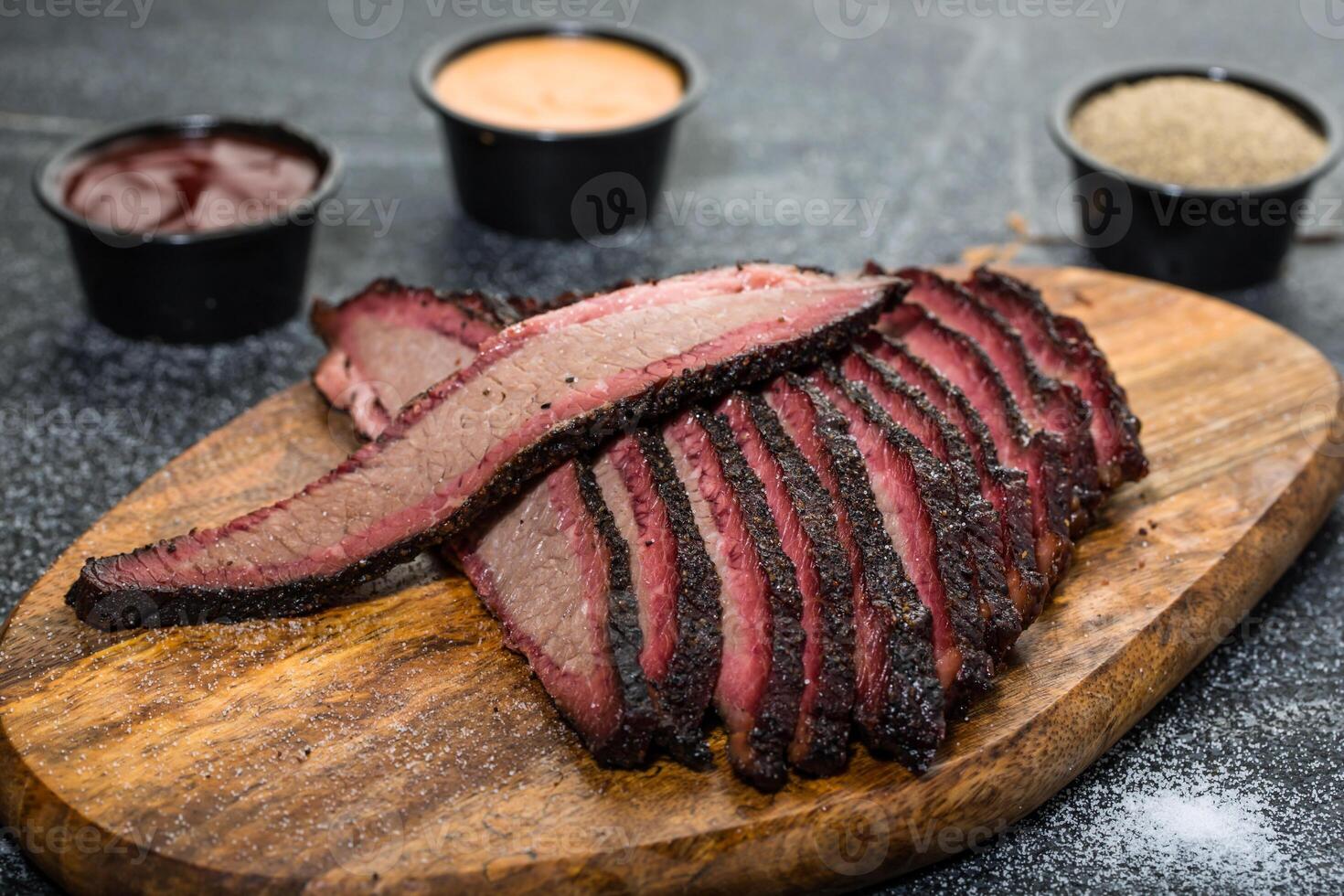 Beef Brisket platter steak meat sliced isolated on wooden board with dip sauce top view of grill food on dark grey background photo